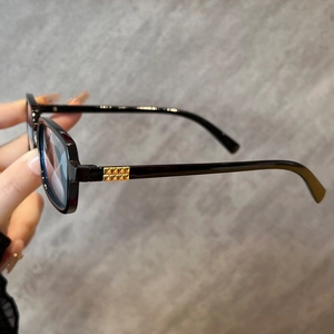 Detail of square black sunglasses featuring gold pyramid studs on the temple