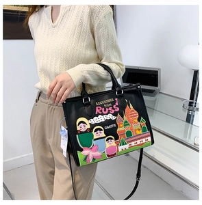 Detail of a black leather tote bag featuring colorful embroidery and dual handles