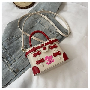 Detail of red and white box bag featuring a pink bunny print and adjustable strap
