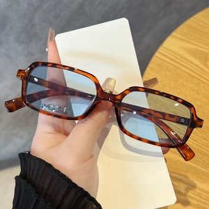 Detail of tortoiseshell square sunglasses with blue lenses and silver chain on the temple