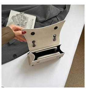 Detail view of cream flap bag interior with dual compartments and metal chain strap