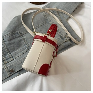Detail of a mini cream and red contrast cylinder bucket bag with gold metal hardware