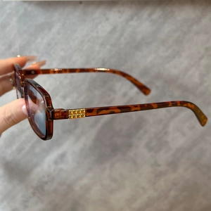 Detail of tortoise square sunglasses with a distinctive gold-toned hinge decoration