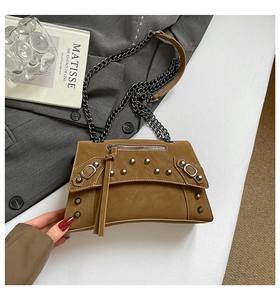 Detailed view of caramel leather crossbody bag with metal rivets and chain strap
