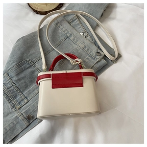 Detail of a contrast color trapezoid box bag in cream and red with golden hardware