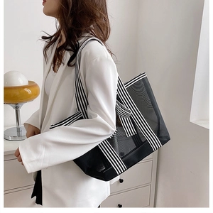 Close-up of black mesh tote bag featuring stylish black and white striped shoulder strap