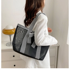 Detail of black mesh tote bag with striped handles and decorative bow on the side