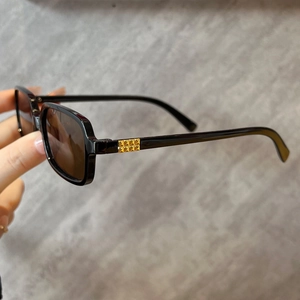 Detail of square vintage sunglasses with gold textured metal temples and brown lenses