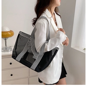 Detail of minimalist black mesh tote bag with high-capacity and striped shoulder strap