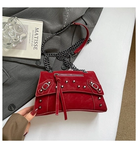 Detail of dark red crossbody bag with silver rivets, metal chain and long leather tassels