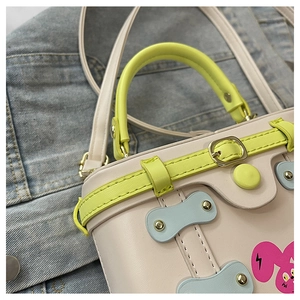 Detailed close-up of cream leather box bag with green handle and cute bunny print