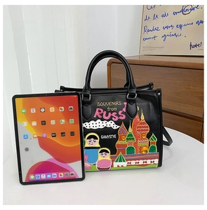 Detail of black leather tote bag with colorful Russian-style embroidery and souvenirs text