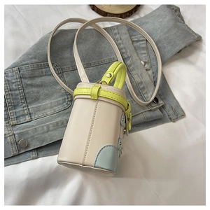 Top view of mini cream crossbody box bag with neon yellow handles on denim background