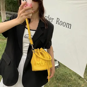 Chic yellow drawstring bucket bag with leather texture and BUCKET lettering print