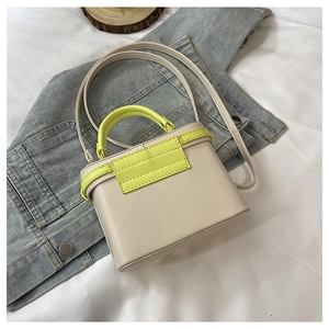 Detail of a chic contrast box bag with neon green handles on a blue denim jacket