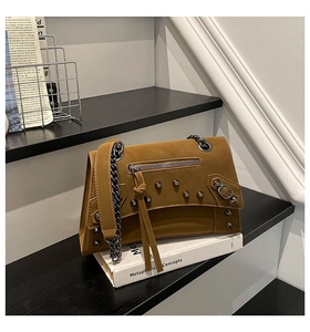 Detailed view of a brown motorcycle style crossbody bag with metal rivets and chain strap