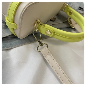Detail of neon green trim and gold metal hardware on the cream leather box bag