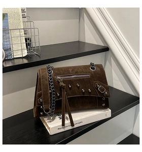 Detailed macro view of dark brown suede bag with silver studs and long leather tassels