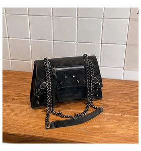 Detail of black motorcycle shoulder bag featuring silver rivets and metal chain strap