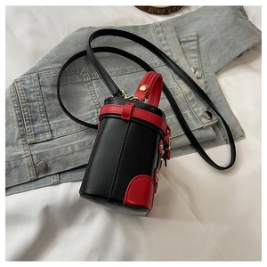 Detail of mini black and red cylinder bucket bag with gold hardware on denim background