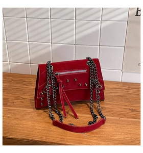 Detail of red punk shoulder bag featuring silver rivets and edgy zipper tassel hardware