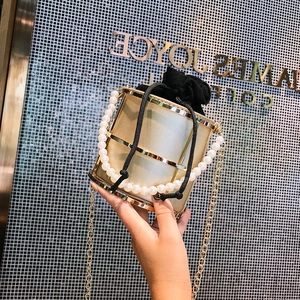 Elegante borsa a secchiello in metallo dorato con interno nero e manico di perle
