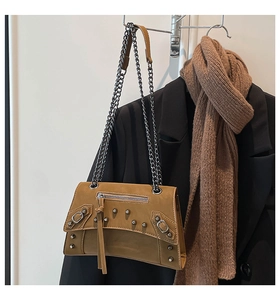 Detail showing camel rivet chain bag paired with black blazer and brown scarf