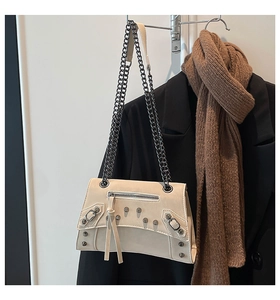 Close-up of off-white leather bag featuring silver rivets, long tassels and chain strap