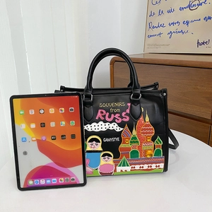 Large black leather tote bag with Russian embroidery shown next to an iPad for size