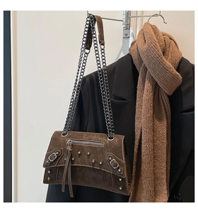 Detail of brown leather crossbody bag with silver metal studs and tassel zippers