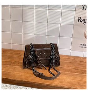 Detail of dark brown faux leather shoulder bag with silver rivets and metal chain strap