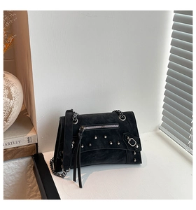 Detail shot of black biker crossbody bag with silver rivets and metallic chain strap