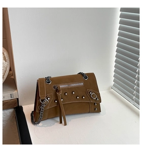 Detailed close-up of brown studded leather bag with silver rivets and metal chain strap