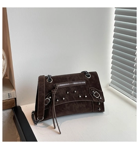 Detail of dark brown rivet motorcycle bag with silver hardware and leather tassels