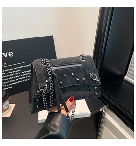 Detail of black motorcycle chain bag with silver studs and tassel on faux leather texture
