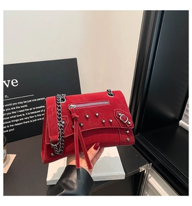 Detail of red suede crossbody bag with silver studs, chain strap and long tassel fringe