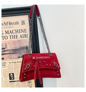 Detailed view of red studded crossbody bag with fringe accents and metal chain strap