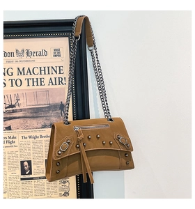 Detail of tan leather crossbody bag featuring silver studs and fringe tassel zipper
