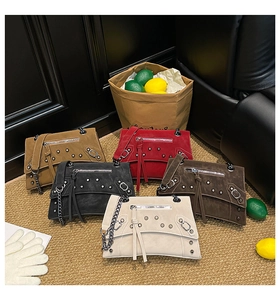 Five chic studded crossbody bags in multiple colors displayed on a woven rug