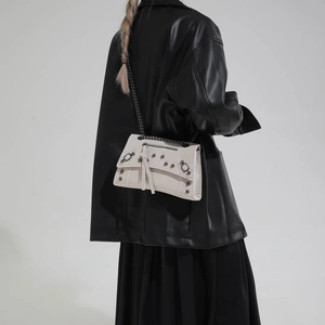 Beige rivet motorcycle crossbody bag with tassels and silver chain on model