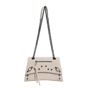 Chic beige crossbody bag with edgy motorcycle studs and dark metal chain straps