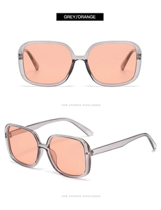 Detail view of square oversized sunglasses with grey transparent frame and orange lenses