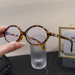 Detail of tortoise shell oval glasses frames with blue light blocking lenses and gold hinge