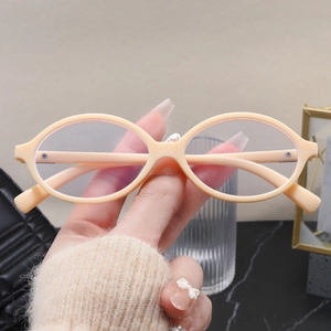 Detailed close-up of oval cream-colored fashion glasses frames held by hand