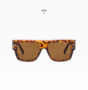 Detail of tortoise shell sunglasses with large flat top frame and gold rivet accents
