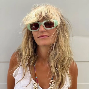 Lunettes de soleil ovales vert clair avec verres rouge foncé portées par un mannequin