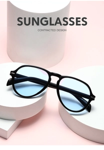Close-up of oversized black pilot sunglasses with blue lenses on a pink pedestal