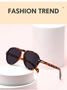 Detailed macro view of tortoiseshell oversized frames on white podium with pink backdrop