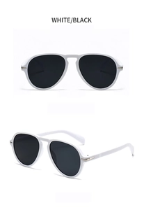 Detail view of white sunglasses with black lenses and gold arrow metal accents