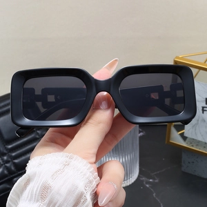 Close-up of black rectangular sunglasses with hollow chain design on the frame legs